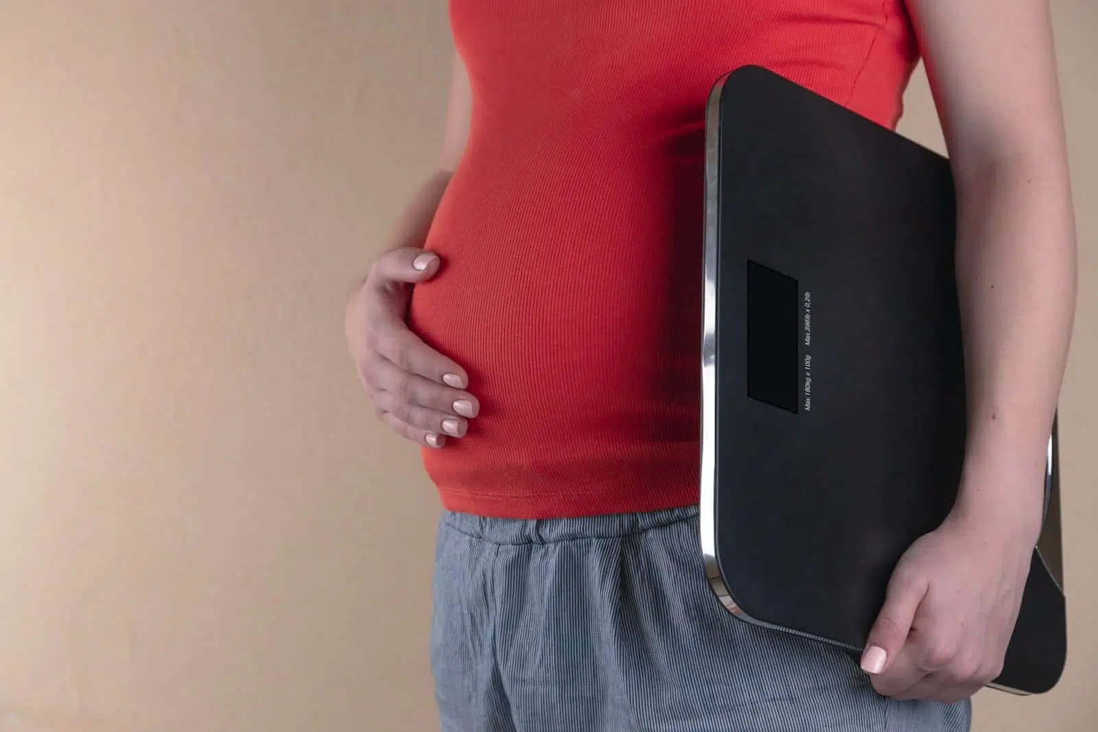 pregnant woman touching her belly and carrying a digital bathrooms cale